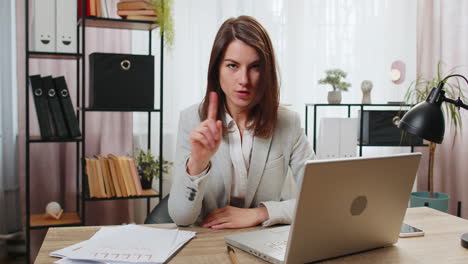 Business-woman-working-on-laptop-computer-shakes-finger-and-saying-no-be-careful-disapproval-sign