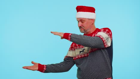 Man-in-red-sweater-Santa-Christmas-showing-thumbs-up-and-pointing-empty-place,-advertising-area