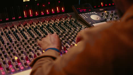 Audio-technician-producing-new-music-at-mixing-console-in-control-room
