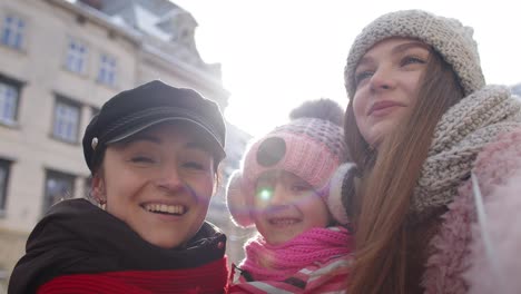 Women-tourists-taking-selfie-photos-on-mobile-phone-with-adoption-child-girl-on-winter-city-street