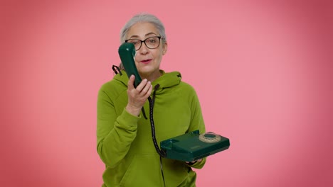 Senior-granny-gray-haired-woman-talking-on-wired-vintage-telephone-of-80s,-says-hey-you-call-me-back