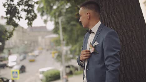 Handsome-groom-stay-near-tree-in-the-city-street.-Wedding-day