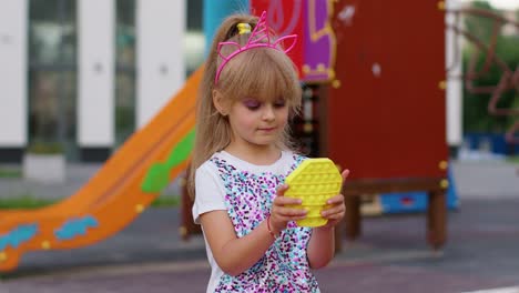 Children-girl-squeezing-presses-colorful-anti-stress-touch-screen-push-pop-it-popular-toy-in-park