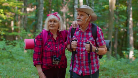 Senior-old-grandmother-grandfather-tourists-enjoying-walking,-hiking-with-backpacks-in-summer-wood