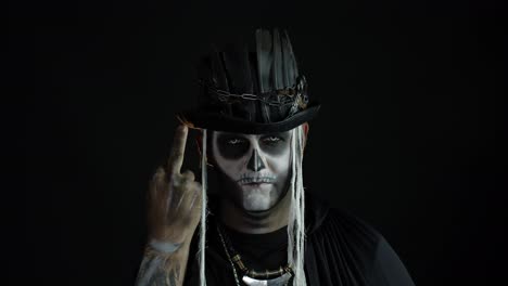 Sinister-man-with-skull-makeup-making-faces-and-showing-middle-finger.-Bad-manner-gesture.-Halloween