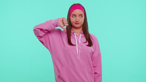 Upset-girl-in-pink-hoodie-showing-thumbs-down-sign-gesture,-disapproval,-dissatisfied,-dislike