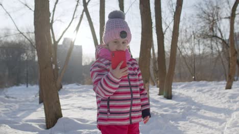 Child-girl-blogger-making-video-call-on-mobile-phone,-selfie-photo-for-social-networksin-winter-park