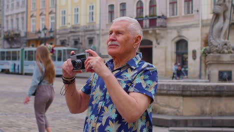 Turista-Senior-Tomando-Fotografías-Con-Cámara-Fotográfica-En-El-Centro-De-La-Ciudad-De-Verano,-Vida-Después-De-La-Jubilación