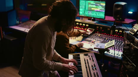 Skilled-musician-performing-in-control-room-at-studio-and-recording-tracks