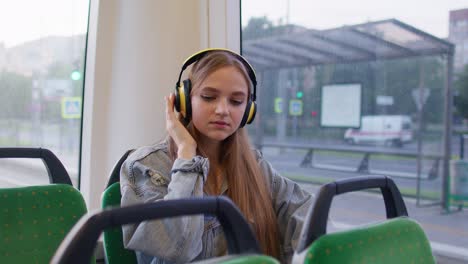 Junge-Frau-Mit-Kopfhörern,-Die-Musik-Hört,-Entspannt-Sich-Beim-Tanzen-Während-Der-Busfahrt-In-Die-Stadt