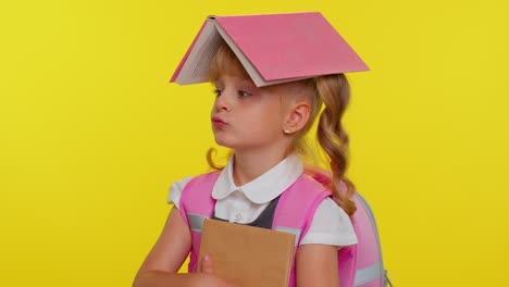 Joyful-funny-schoolgirl-kid-with-book-on-head-making-playful-silly-facial-expressions-fooling-around