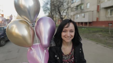Hübsche-Frau,-Die-Die-Straße-Entlang-Geht-Und-Ballons-Mit-Helium-Hält