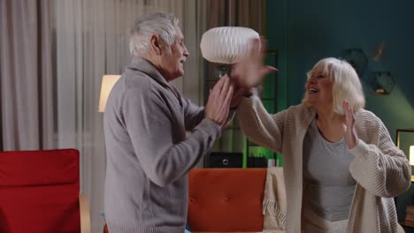 Happy-senior-people-couple-dancing-at-home-relaxing-having-fun-with-modern-music-smiling-at-home