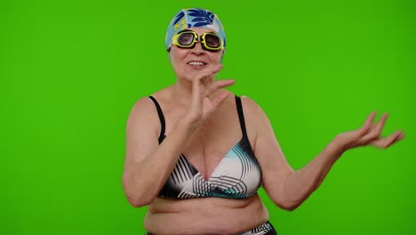 Senior-pensioner-woman-tourist-in-swimsuit-bra,-swim-goggles-and-hat-dancing-celebrating,-smiling