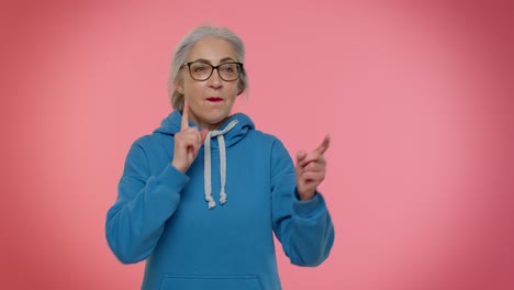 Senior-old-granny-woman-pointing-around-with-finger-gun-gesture,-shooting-killing-with-hand-pistol