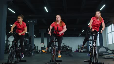 Gruppe-Sportlicher-Mädchen,-Die-Aerobic-Trainingsübungen-Auf-Dem-Fahrradergometer-Im-Fitnessstudio-Durchführen