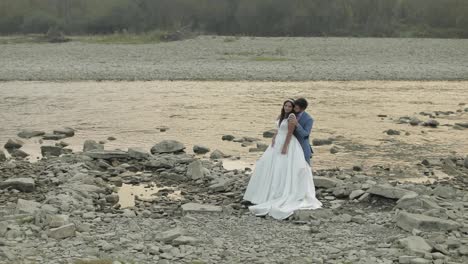 Wedding-couple-standing-near-mountain-river.-Groom-and-bride-in-love