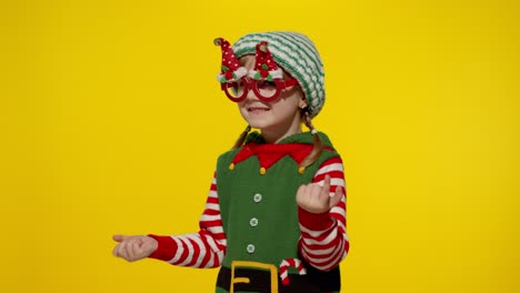 Kid-girl-in-Christmas-elf-Santa-helper-costume-dancing,-fooling-around.-New-Year-holiday-celebration