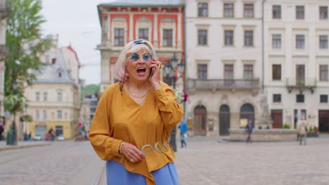 Anciana-Turista-Con-Ropa-Elegante-Hablando-Por-Teléfono-Móvil-Mientras-Camina-Por-Las-Calles-De-La-Ciudad