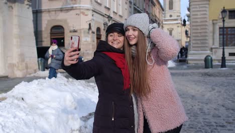 Two-young-smiling-women-tourists-bloggers-taking-selfie-photos-portrait,-video-conferencing-call