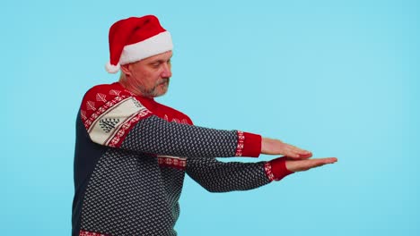 Man-wears-red-Christmas-deer-sweater-showing-thumbs-up-and-pointing-at-on-blank-advertisement-space