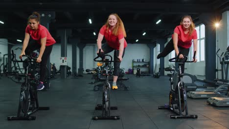 Grupo-De-Mujeres-Atléticas-Montando-En-Rutina-De-Entrenamiento-De-Bicicleta-Estacionaria-Giratoria-En-El-Gimnasio,-Pérdida-De-Peso-En-Interiores