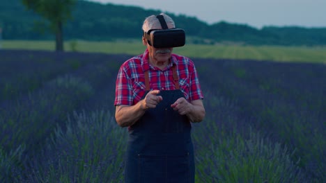 Senior-grandfather-farmer-in-virtual-reality-helmet-managing-quality-in-field-of-lavender-flowers