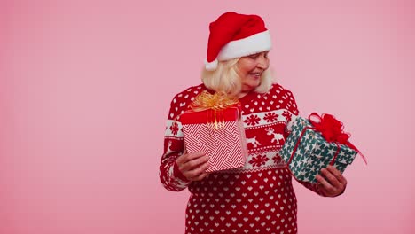 Grandmother-in-Santa-sweater-presenting-one-Christmas-gift-box,-stretches-out-his-hands-to-camera