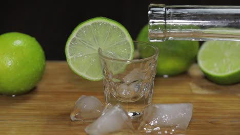 Pour-vodka-or-tequila-from-a-bottle-into-shot-glasses-with-ice-cubes