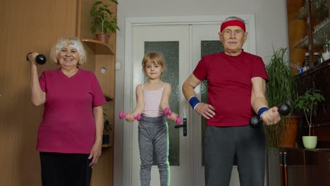 Active-senior-couple-grandmother-grandfather-with-child-kid-girl-doing-fitness-dumbbells-exercises