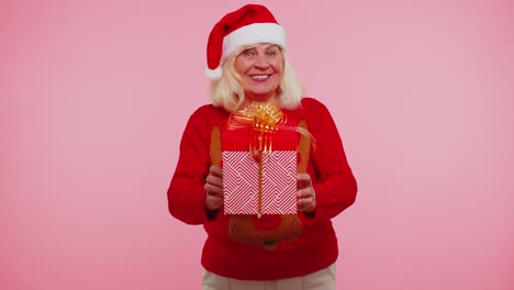 Ältere-Großmutter-Im-Neujahrspullover-Und--hut-Präsentiert-Weihnachtsgeschenkbox,-Einkaufsverkaufsfeiertage