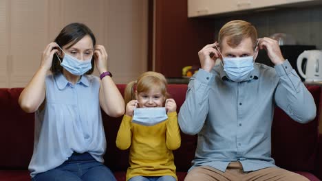 Coronavirus-quarantine-lockdown.-Mother,-father-and-daughter-puts-medical-masks-on-faces-at-home