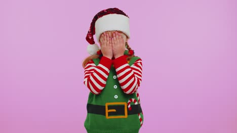 Girl-kid-toddler-Santa-Christmas-Elf-fooling-around-having-closing-eyes-with-hand-and-spying-through