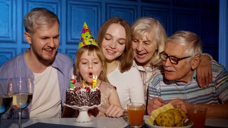 Mädchen-Feiert-Geburtstagsparty-Mit-Eltern,-ältere-Großelternfamilie-Bläst-Kerzen-Auf-Kuchen-Aus