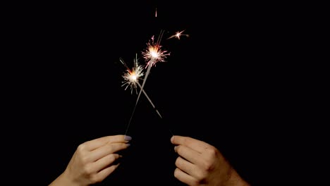 Hands-holding-and-waving-Bengal-fires.-New-year-sparkler-candle-burning-on-a-black-background