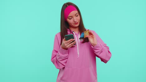 Teen-girl-using-credit-bank-cards-and-smartphone-while-transferring-money,-purchases-online-shopping