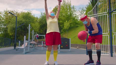 Active-senior-man-woman-playing-basketball-on-sports-playground-court-during-coronavirus-pandemic