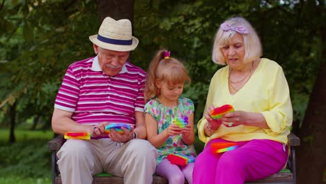Smiling-senior-grandmother-grandfather-with-granddaughter-playing-squeezing-anti-stress-toy-game