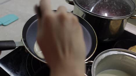 The-process-of-cooking-homemade-pancakes.-Woman-pours-pancake-dough-on-pan