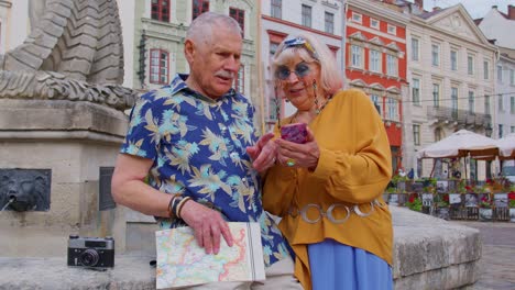 Senior-stylish-couple-tourists-man,-woman,-grandmother,-grandfather-looking-for-way-using-smartphone