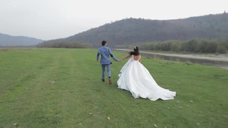 Wedding-couple-running-near-mountain-river.-Groom-and-bride-in-love