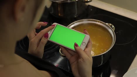Una-Mujer-Sostiene-Un-Teléfono-Inteligente-Con-Una-Pantalla-Verde-Y-Cocina-Sopa