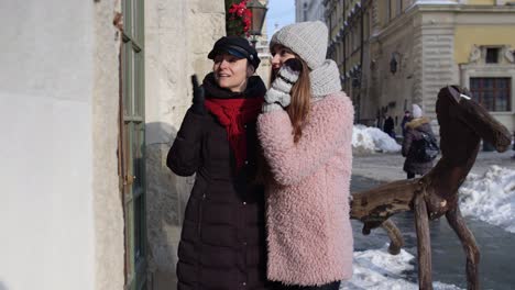 Zwei-Lächelnde-Touristinnen-Schauen-Auf-Das-Schaufenster-In-Der-Stadtstraße,-Ein-Familienpaar-Redet-Und-Umarmt