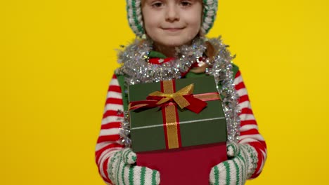 Kid-girl-Christmas-elf-Santa-helper-giving-present-gift-box-to-camera.-Happy-New-Year-holidays