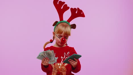 Mädchen-In-Roten-Weihnachtshirschgeweihen-Schaut-Auf-Smartphone-Und-Freut-Sich-über-Sieg,-Erfolg,-Glück-Und-Geld