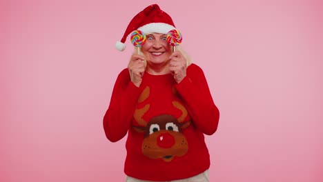 Großmutter-Im-Weihnachtspullover-Hält-Süßigkeiten-Gestreifte-Lutscher,-Die-Sich-Hinter-Ihnen-Verstecken-Und-Herumalbern