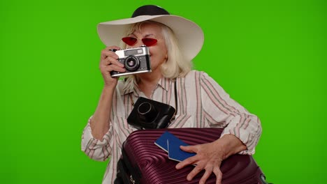 Senior-woman-tourist-photographer-taking-photos-on-retro-camera-and-smiling-on-chroma-key-background