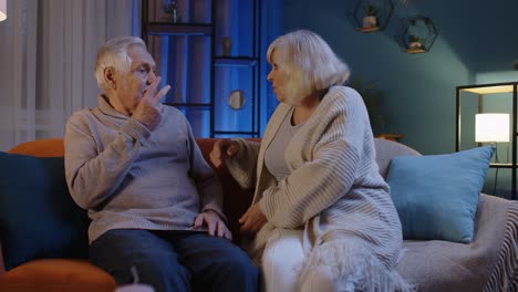Portrait-of-angry-mature-grandparents-couple-quarreling-in-evening-at-home-sofa,-crisis,-conflicts
