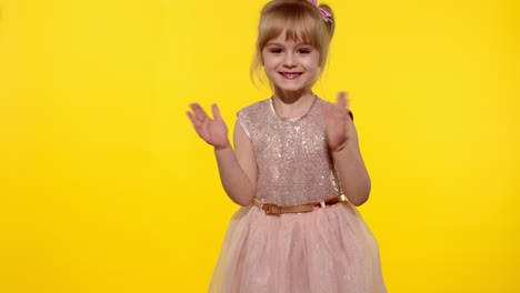 Little-blonde-child-girl-5-6-years-old-smiling,-dancing,-celebrating-on-yellow-studio-background