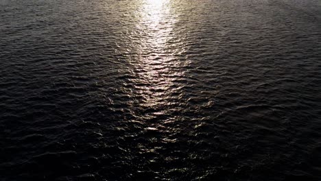 Aerial-wide-angle-view-of-dark-Caribbean-ocean-water-as-drone-flies-over-to-setting-sun